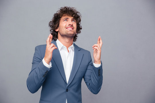 Portrait of a businessman praying with crossed fingers