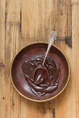 chocolate in dish with spoon on brown background