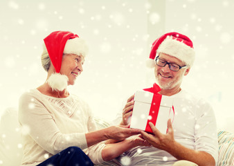 happy senior couple in santa hats with gift box