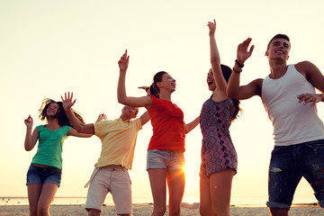 Obraz premium smiling friends dancing on summer beach