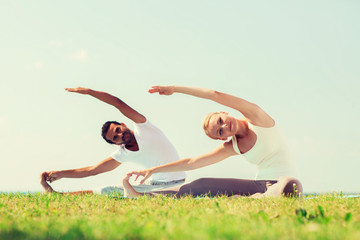 Fototapeta premium smiling couple making yoga exercises outdoors