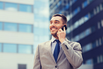 smiling businessman with smartphone outdoors