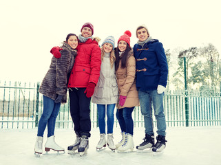 happy friends ice skating on rink outdoors