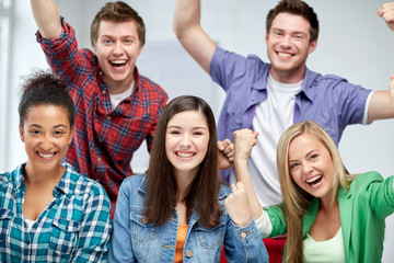 group of happy students making triumph gesture