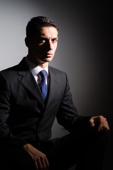 Fototapeta premium Young businessman in dark studio