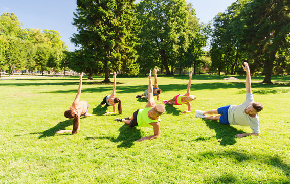 group of happy friends exercising outdoors