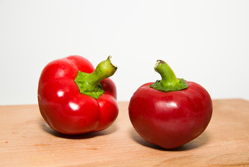 Two ripe red peppers on over white
