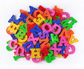 Heap of plastic colored alphabet letters on a white