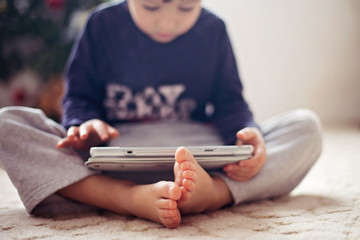 Cute little boys feet, boy playing on tablet
