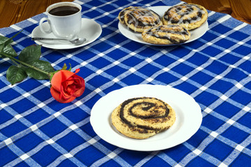 Homemade cake with poppy seeds in the shape of a snail with a cup of coffee, red rose