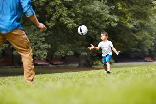 A man and a boy playing football in the park