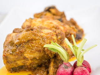 Malaysian dish Rendang Ayam or dry curry chicken in a white plate over wooden background