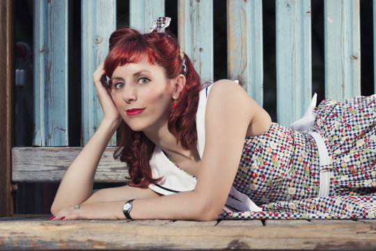 View of pinup young woman in vintage style clothing on a playground.