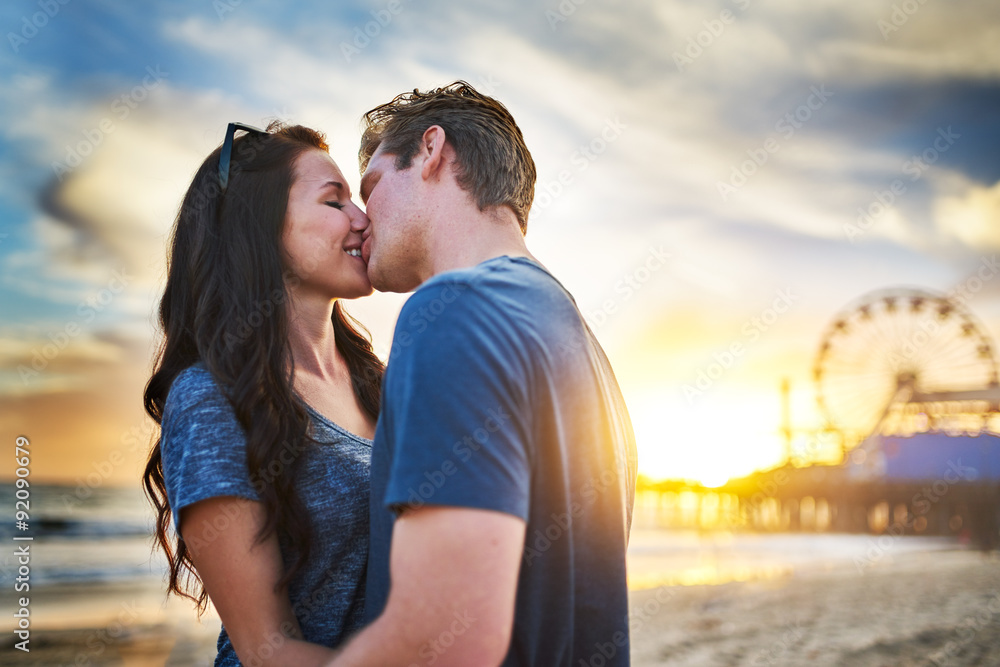 Wall mural romantic couple kissing at santa monica