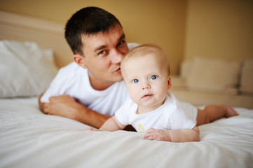 father kissing baby on the bed
