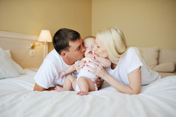 Fototapeta na wymiar parents kiss the baby in bed