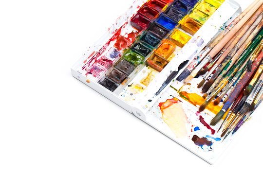 Used water-color paint-box and dirty artist paint brushes. Top view. Isolated image with space for your text