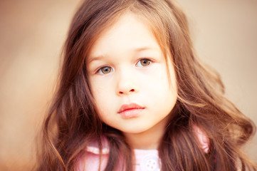 Naklejka premium Closeup portrait of cute kid girl 4-5 year old posing outdoors. Looking at camera. Childhood. 