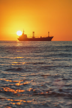 Cargo ship sailing at sunrise near the harbour
