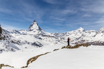 Fototapeta na wymiar A woman standing on the snow in the background of Matterhorn.