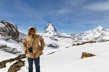 A man in camouflage winter coat standing in front of the background of Matterhorn.