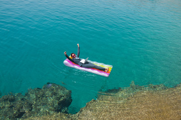Successful  businesswoman with laptop on floating mattress in red sea  