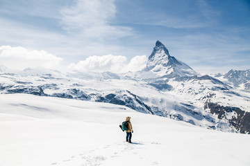 Een man die in de sneeuw staat en naar de achtergrond van de Matterhorn kijkt.