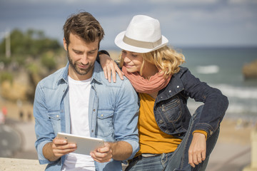 young couple using a digital tablet at seaside town