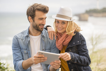 young couple using a digital tablet at seaside town