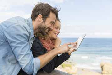 young couple using a digital tablet at seaside town