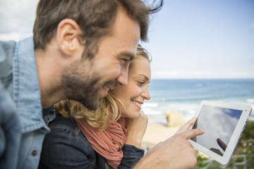 Fototapeta premium young couple using a digital tablet at seaside town