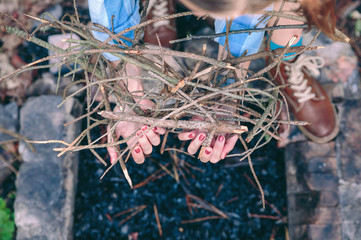 Female hands holding firewood for bonfire over coals background