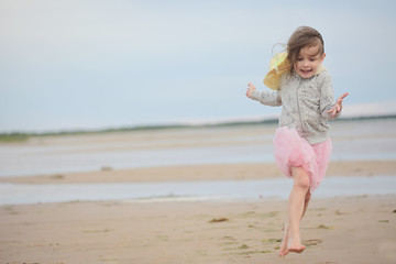 Little girl running on sand against sea and sky