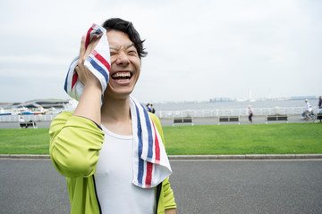 Naklejka premium Young Asian man using a towel after exercise at a park