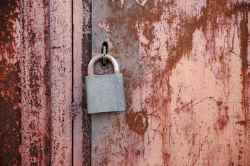 On the old wooden door, installed a rusty padlock