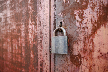 On the old wooden door, installed a rusty padlock