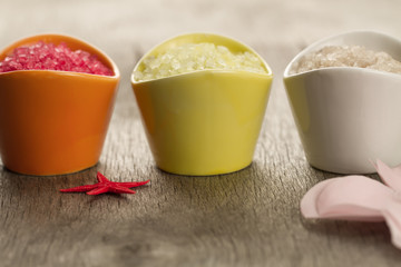 Colorful sea salts and seashells for the bathroom on wooden background. Spa, aromatherapy.