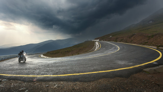 Fototapeta Driving a motorcycle on alpine highway toward the storm