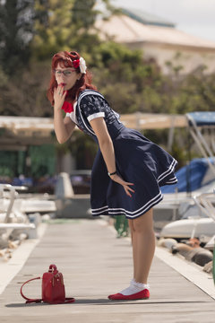 View of pinup young woman in vintage style clothing on a marina.