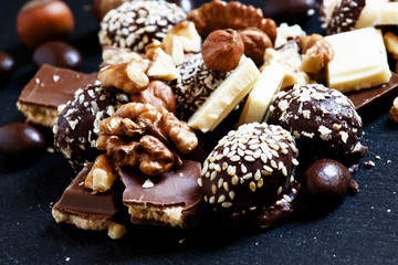 Chocolates, sweets, hazelnuts and walnuts on a dark background,