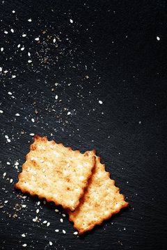 Sweet crackers, sesame, sugar grains on a dark background, top v