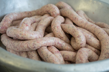 Raw sausages in a metal bowl