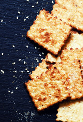 Sweet crackers, sesame, sugar grains on a dark background, top v