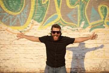 Obraz premium Chico atractivo y joven ecuchando música con auriculares, sonriendo y cantando