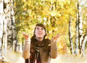 Beautiful girl in autumn park catch hands falling leaves