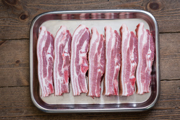 Belly of pork in a silver tray on wooden background