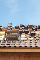 House under construction. Roofing tiles with open skylight