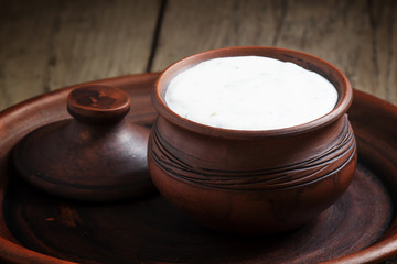 White cream sauce in brown clay pot  in a rustic style, selectiv