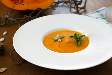 Homemade creamy pumpkin soup on table with autumn decorations.
