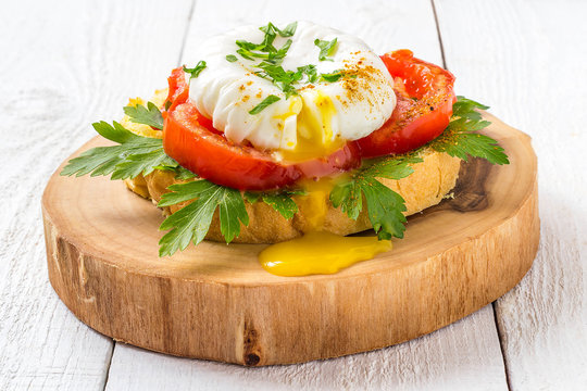 Poached egg on toast with tomatoes and parsley for breakfast